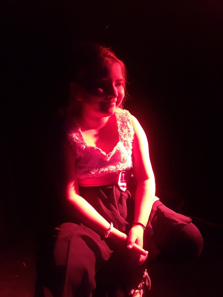 Student onstage with artistic lighting