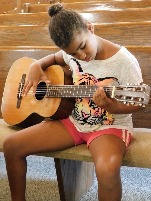 Student plays the guitar at Choral Camp lessons.
